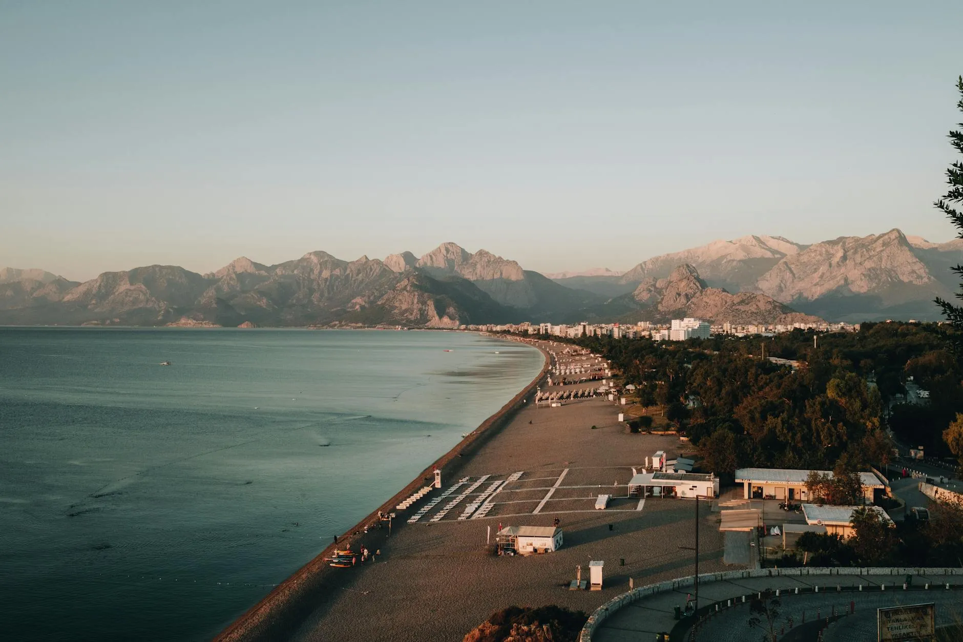Explore Antalya's beautiful coastline with mountains, beach, and resort town at dawn.