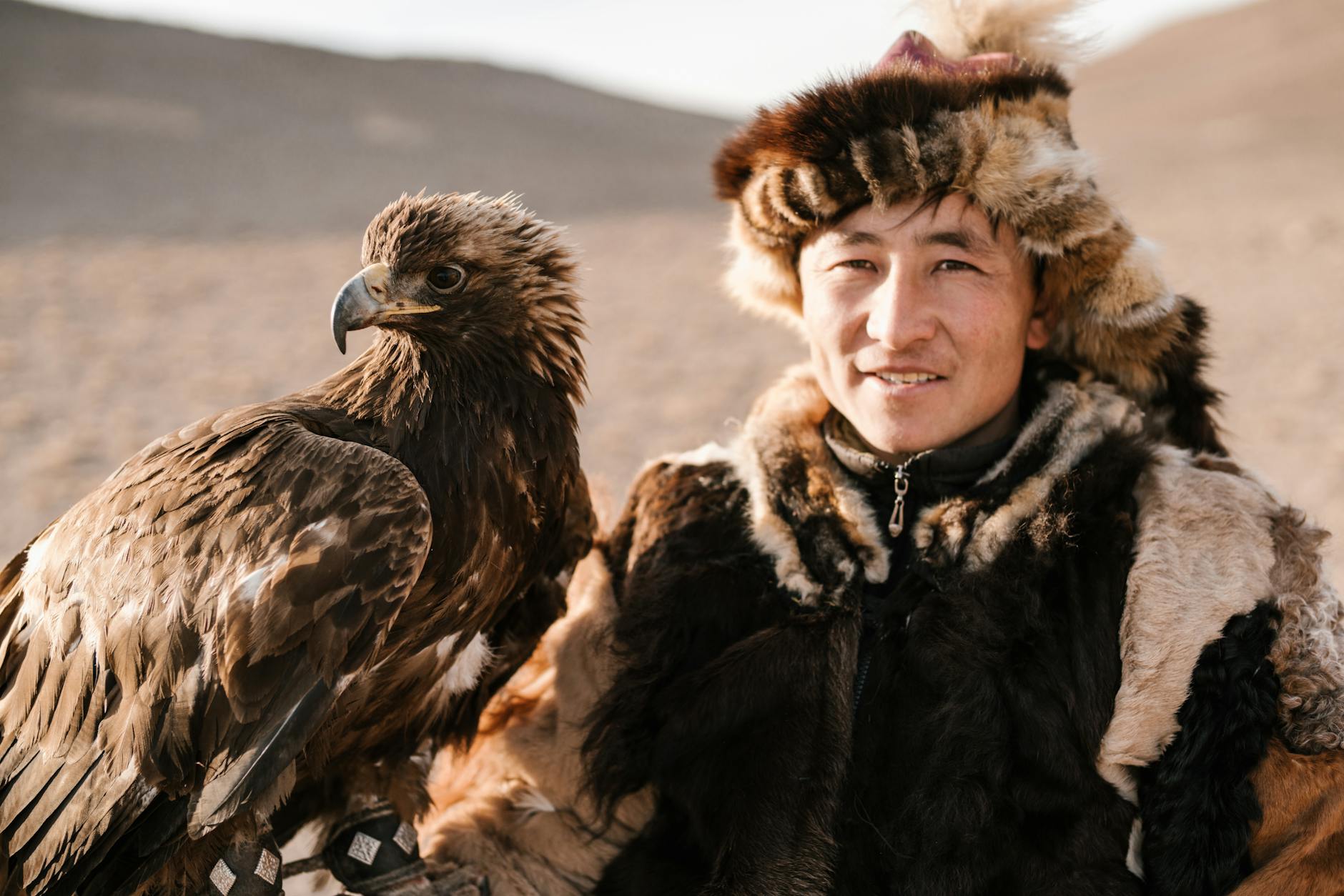 Portrait of a Mongolian falconer with a majestic eagle on a steppe landscape.