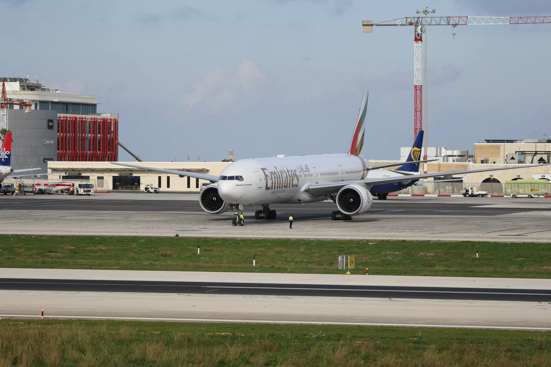 Emirates airplane taxiing on a runway at an airport on a clear day.