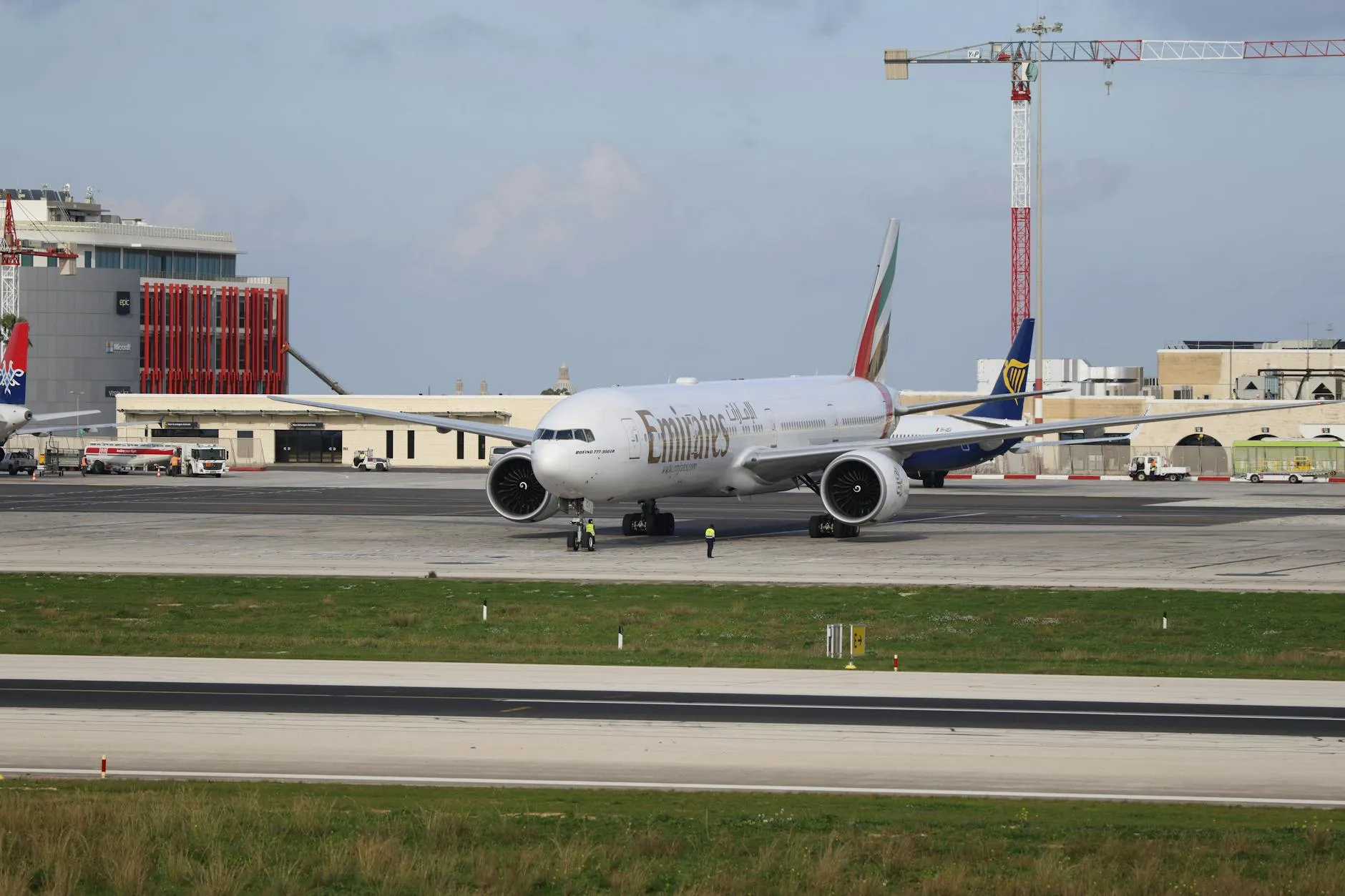 Emirates airplane taxiing on a runway at an airport on a clear day.