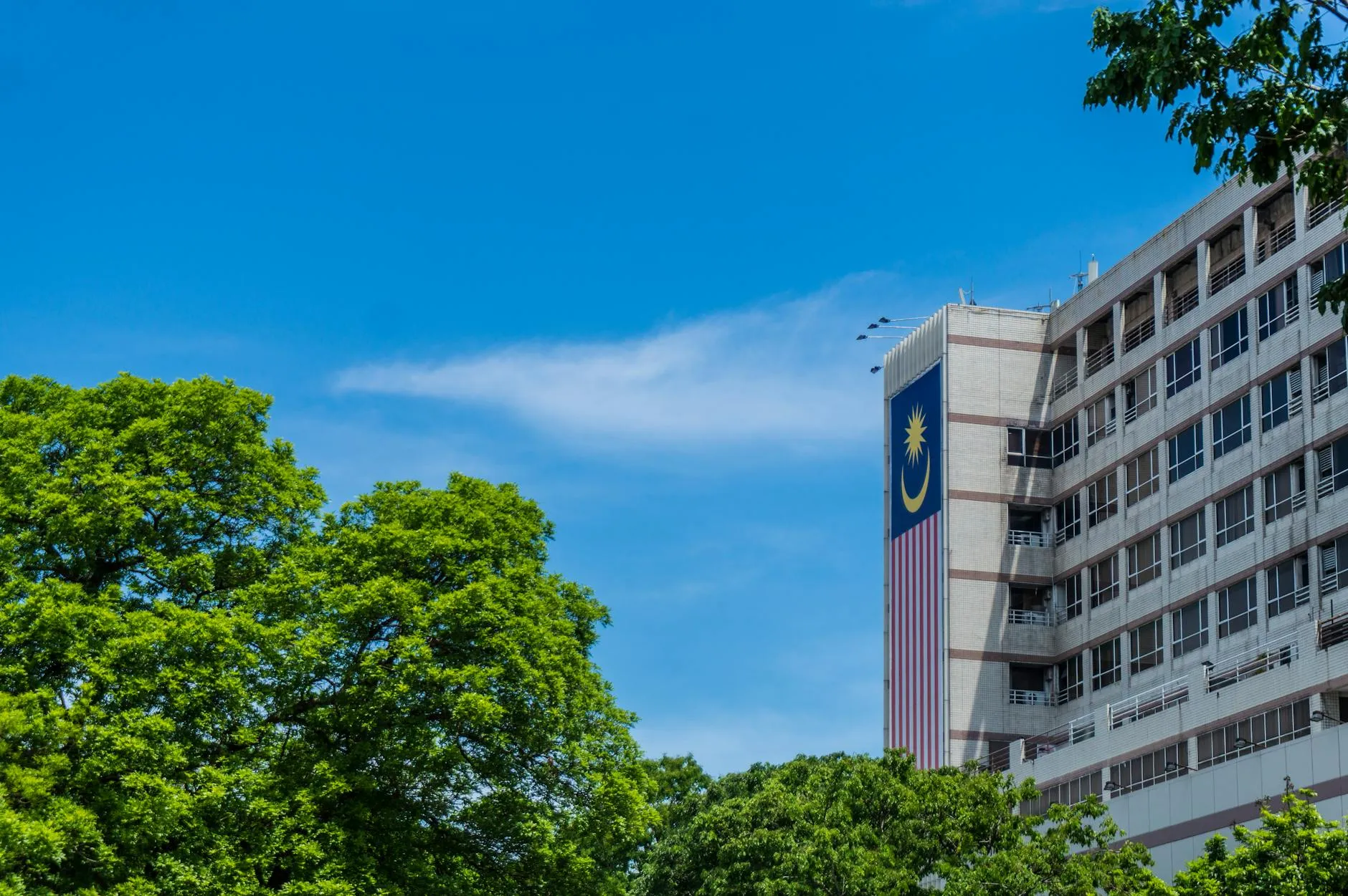 Kota Kinabalu, Sabah, Malaysia — Modern architectural building with Malaysian flag and greenery in Kota Kinabalu, Sabah, Malaysia.