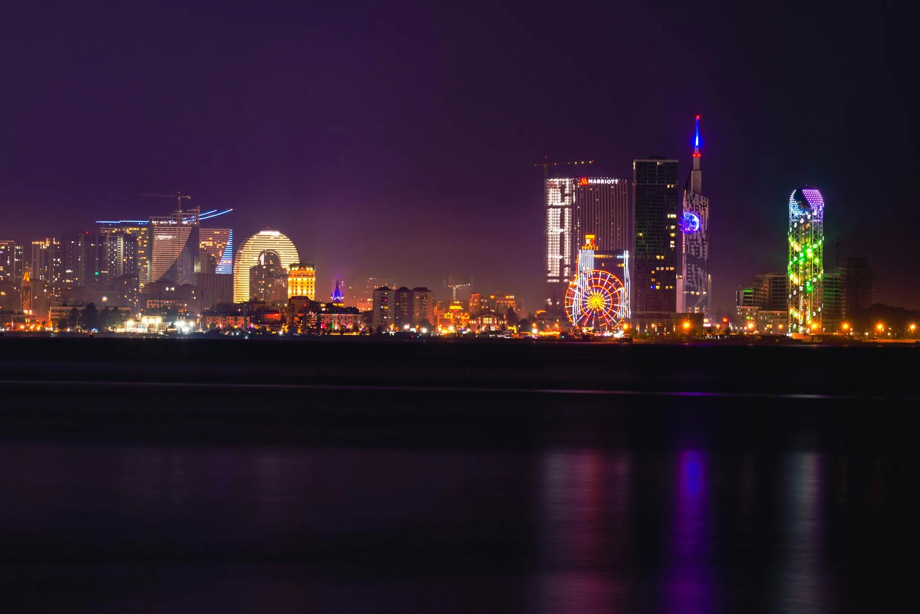 Batumi Georgia — Explore the illuminated Batumi skyline featuring colorful skyscrapers and a Ferris wheel along the Black Sea waterfront.