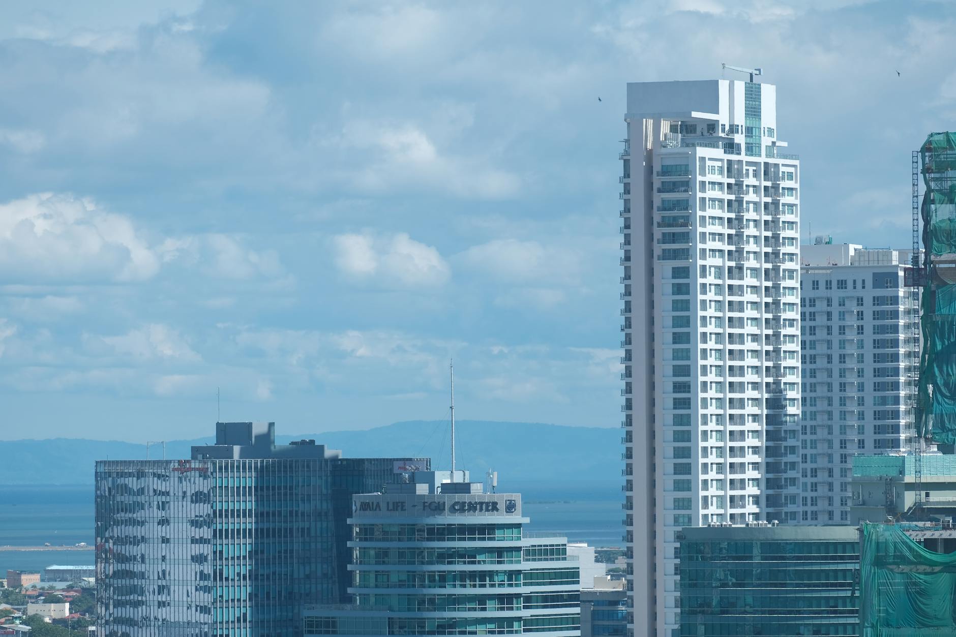 High-rise buildings in the vibrant skyline of Cebu City, under a bright blue sky.