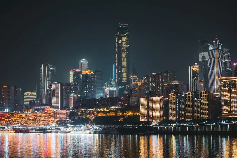 A vibrant view of Chongqing's illuminated skyline reflecting on the water at night.