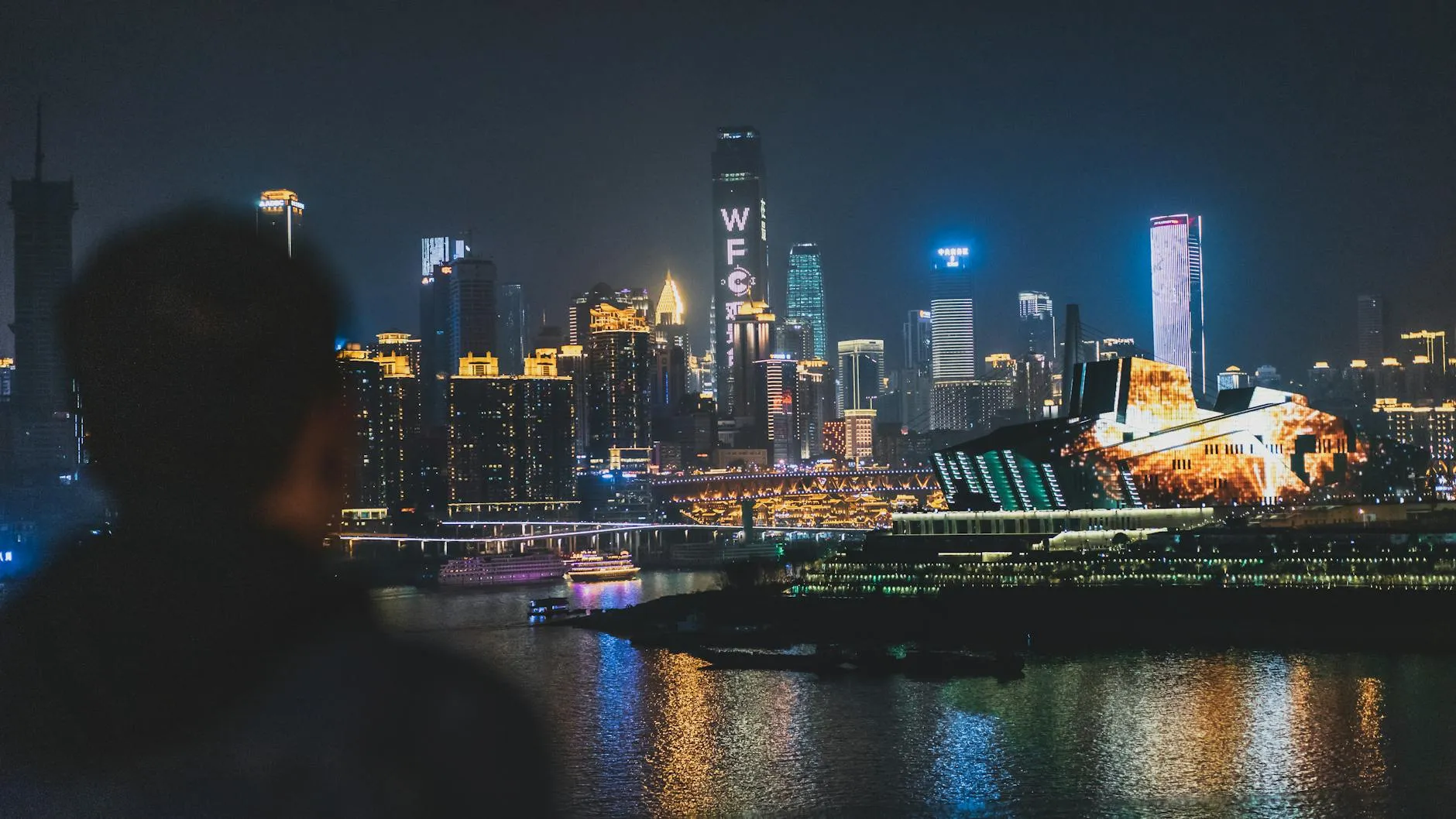 Chongqing Jiangbei International Airport (CKG) — Back view unrecognizable blurred male enjoying amazing view of contemporary illuminated embankment in Chungking China during night