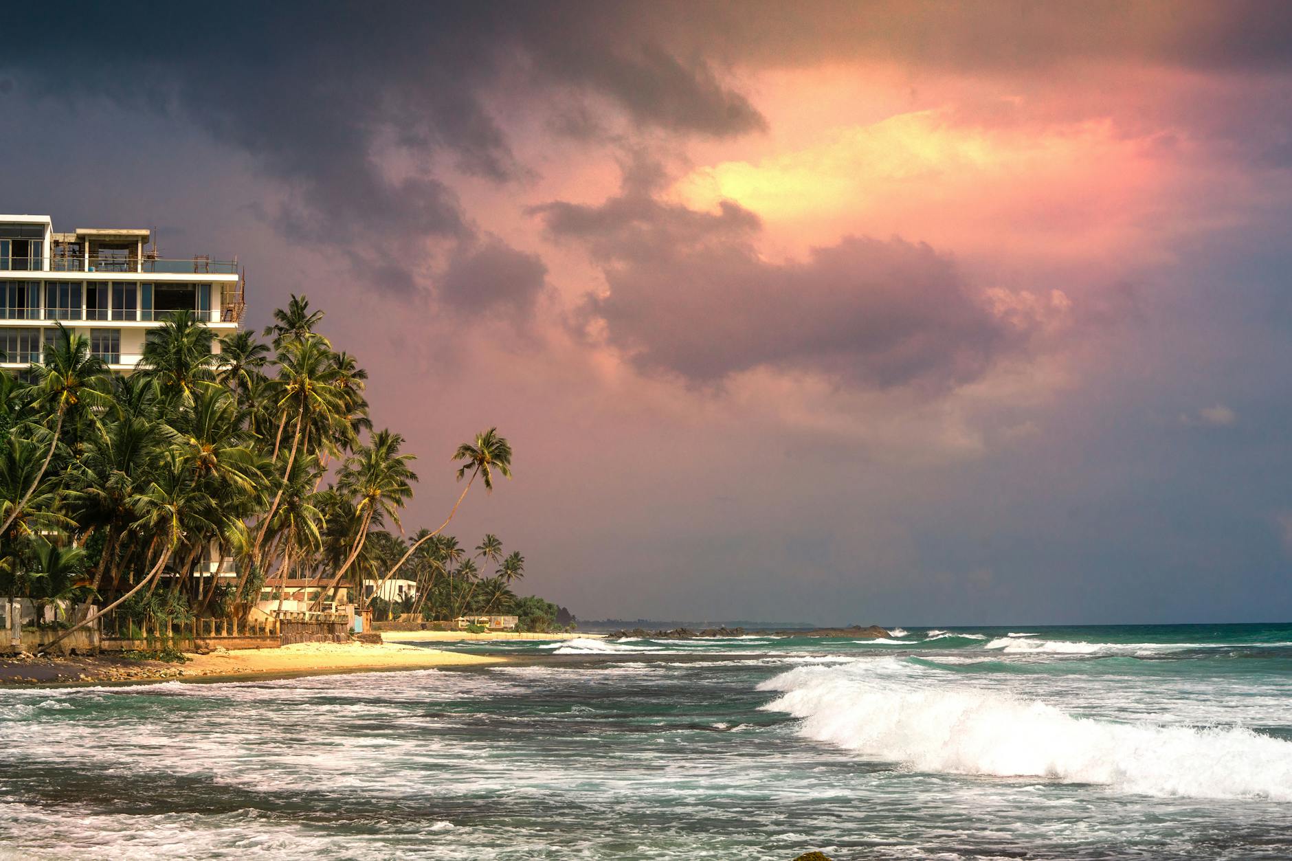Stunning sunset at Unawatuna Beach, Sri Lanka, with palm trees and ocean waves.