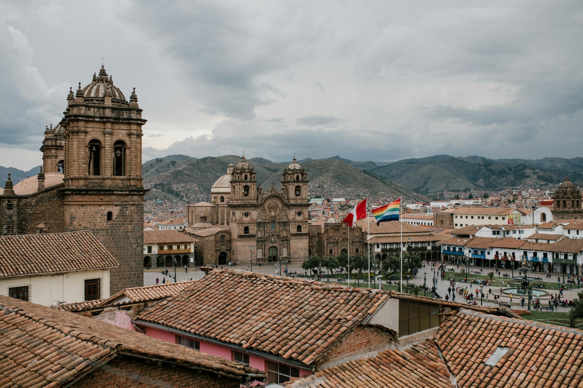 Cusco, Peru — High angle of shabby tile roofs of old buildings and Plaza De Armas with national flags and church in Cusco Peru