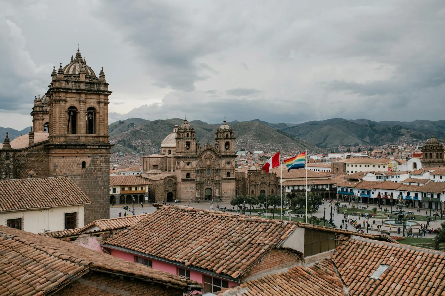 Cusco, Peru — High angle of shabby tile roofs of old buildings and Plaza De Armas with national flags and church in Cusco Peru