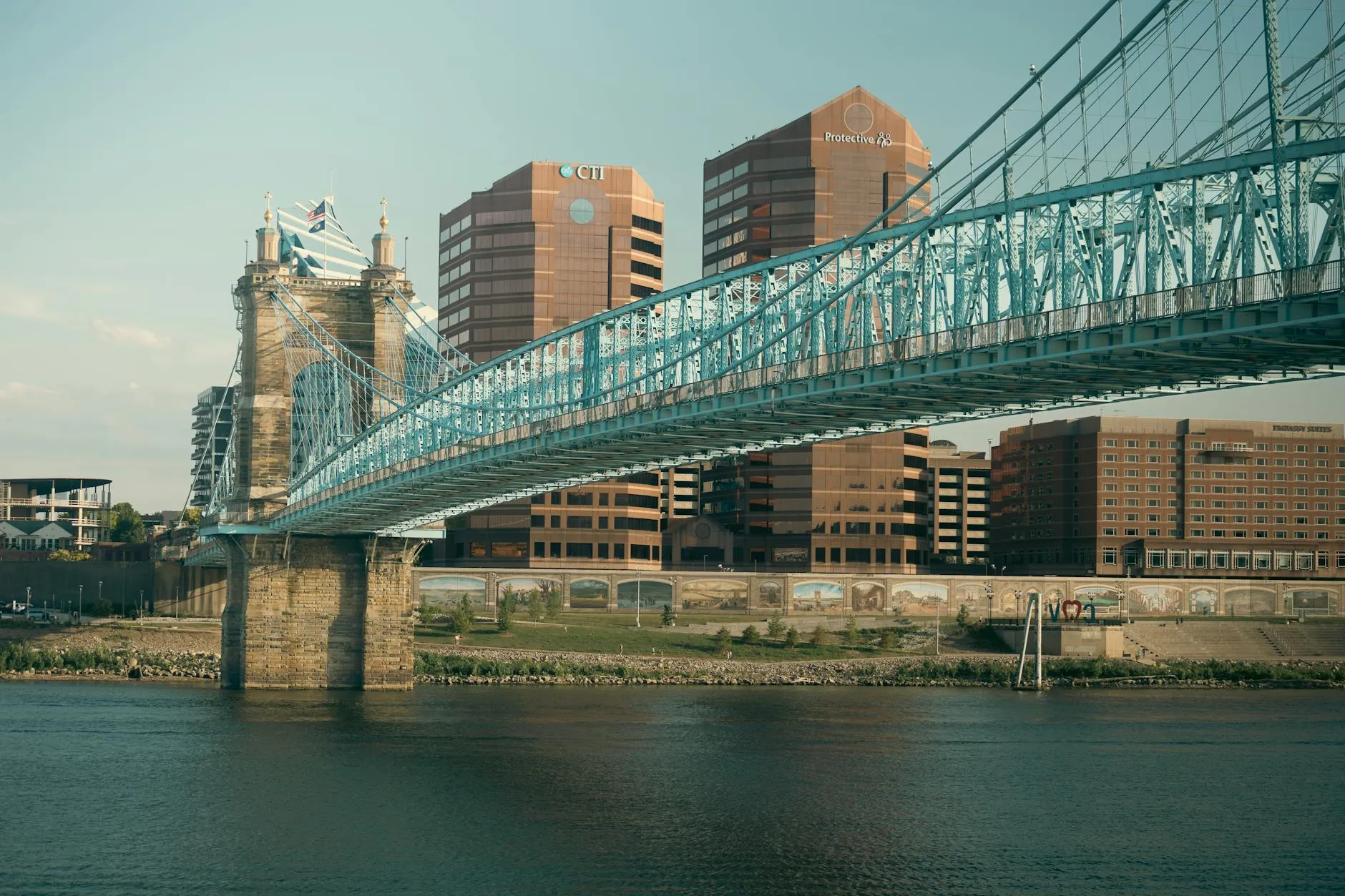 Cincinnati Ohio — A view of Cincinnati's skyline featuring the iconic Roebling Suspension Bridge over the Ohio River at sunset.