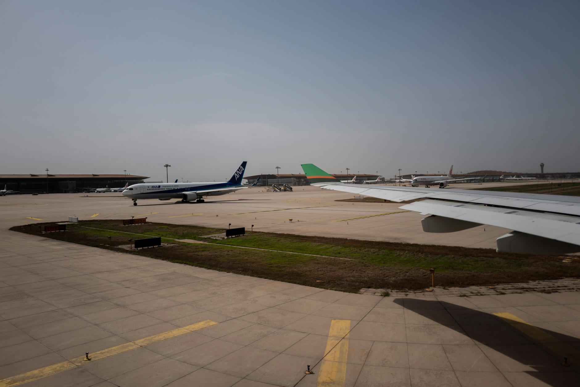 Airplanes taxiing on runway at a busy airport under clear skies.