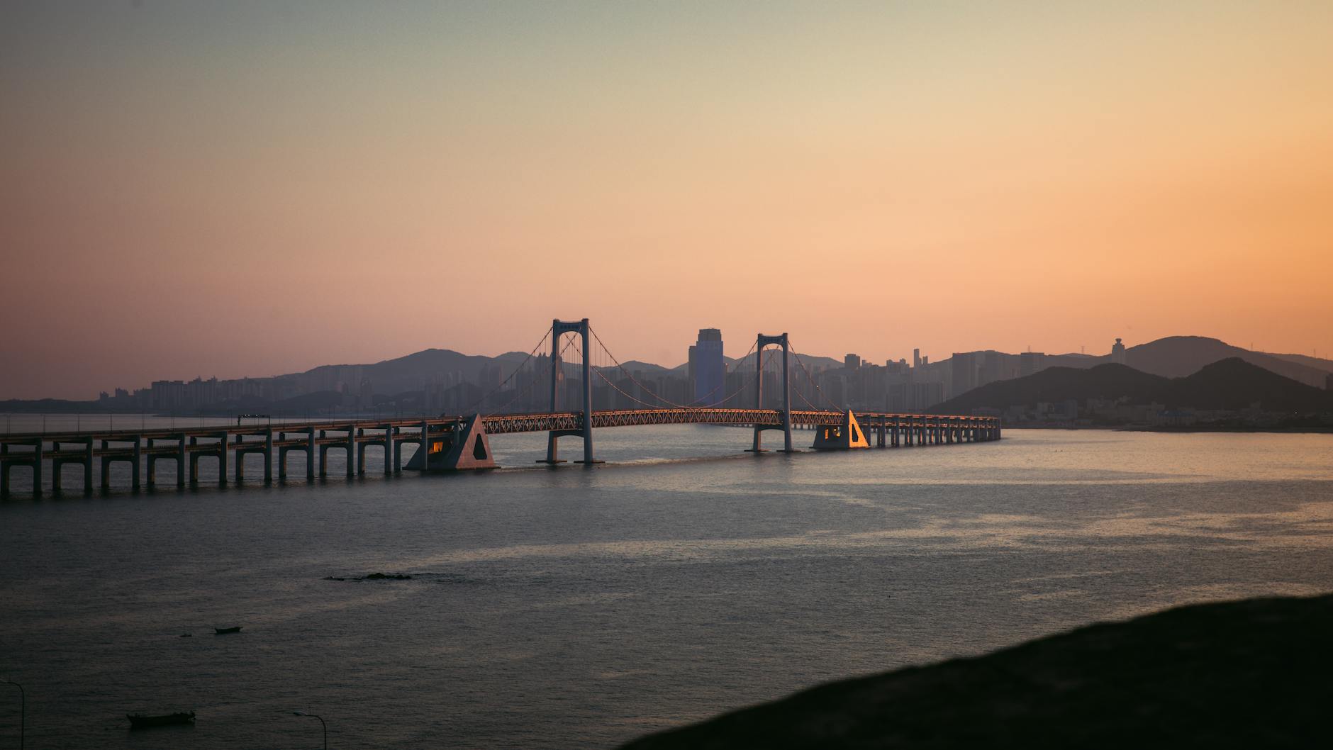 Dalian, China — Explore the scenic beauty of Dalian's Xinghai Bay Bridge bathed in sunset light.