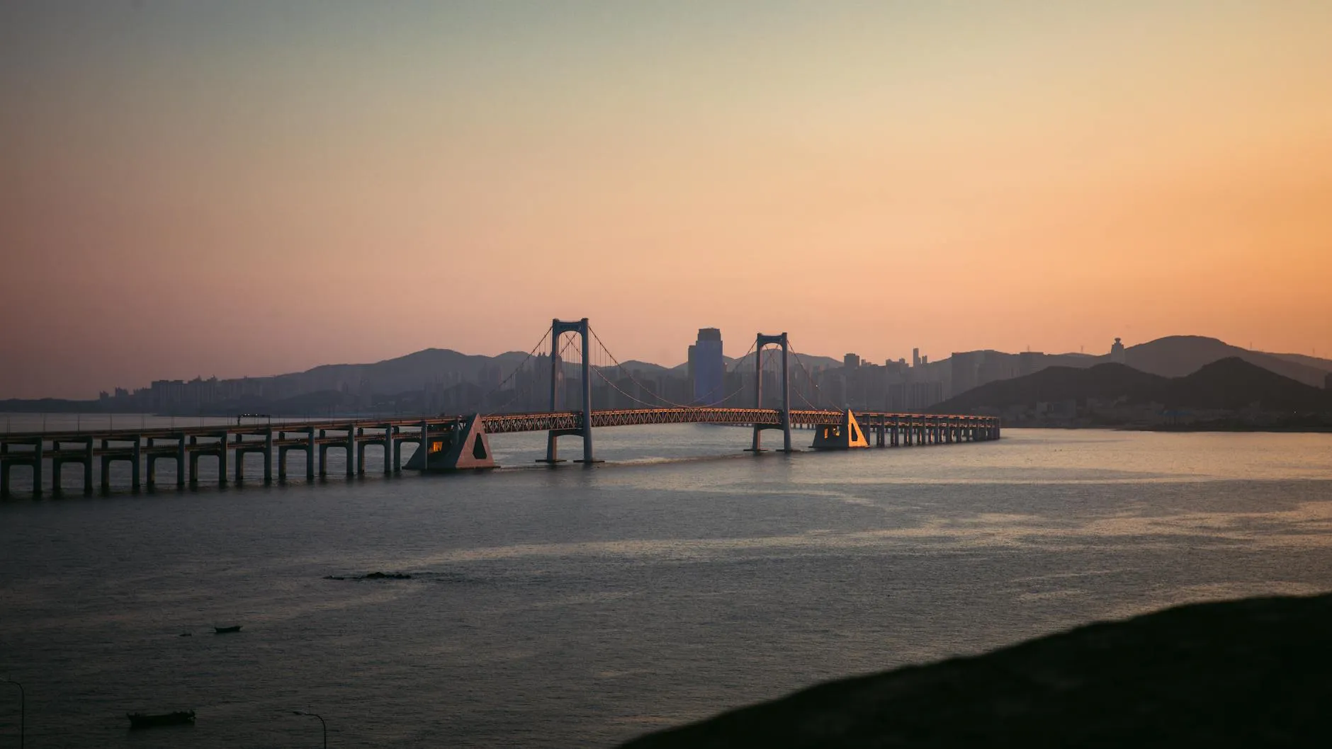Dalian, China — Explore the scenic beauty of Dalian's Xinghai Bay Bridge bathed in sunset light.