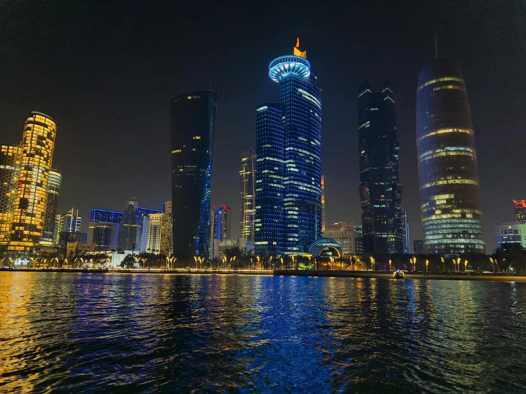 Captivating night scene of Doha's illuminated skyline reflecting on water in Qatar.