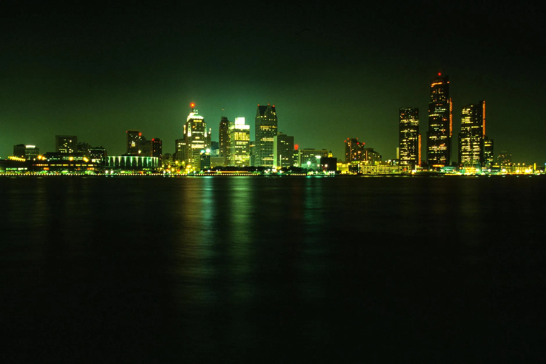 Detroit Michigan — Stunning nighttime view of Detroit's illuminated skyline across a calm river under a dark sky.