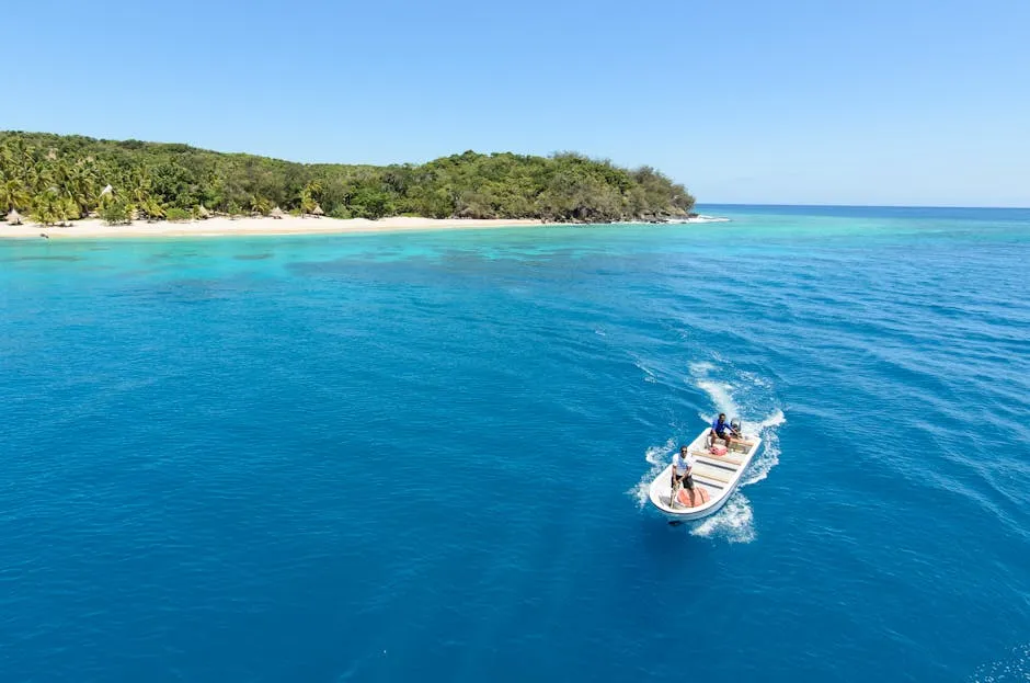 A stunning aerial shot of a tropical island with a motorboat on the vibrant blue sea in Fiji.