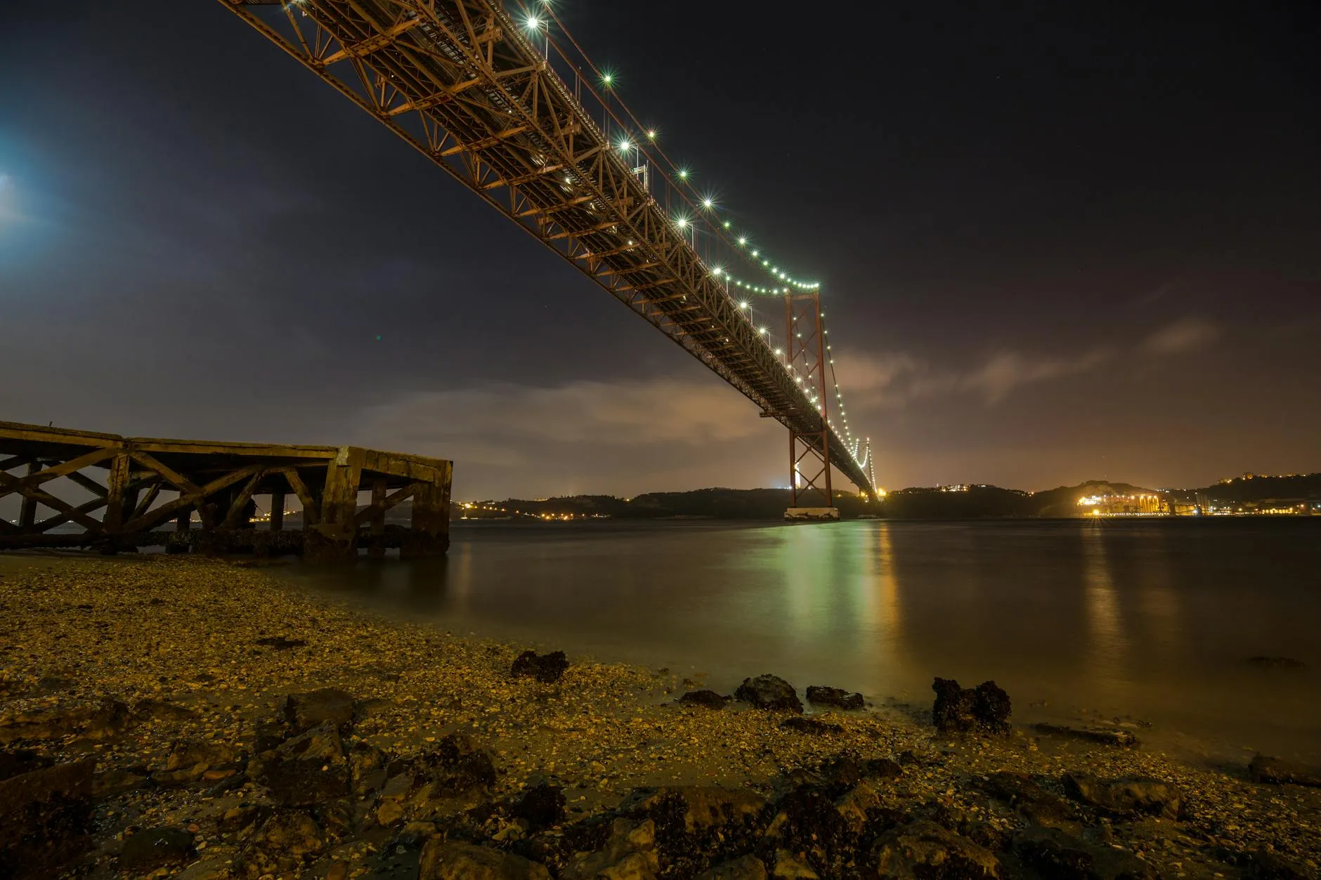 Florianópolis, Brazil — Stunning night view of the Hercilio Luz Bridge illuminated over calm ocean waters.