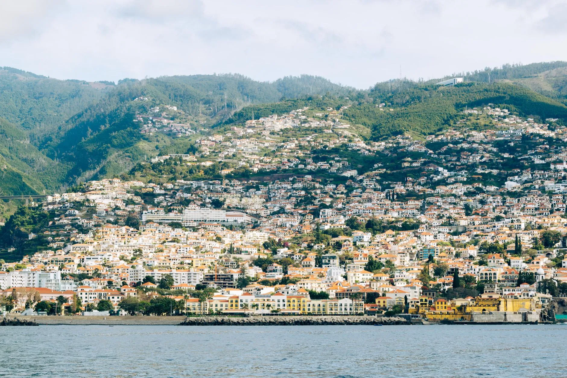 Cristiano Ronaldo Madeira International Airport (FNC) — Scenic view of Madeira's hillside urban landscape with vibrant architecture and lush green hills.