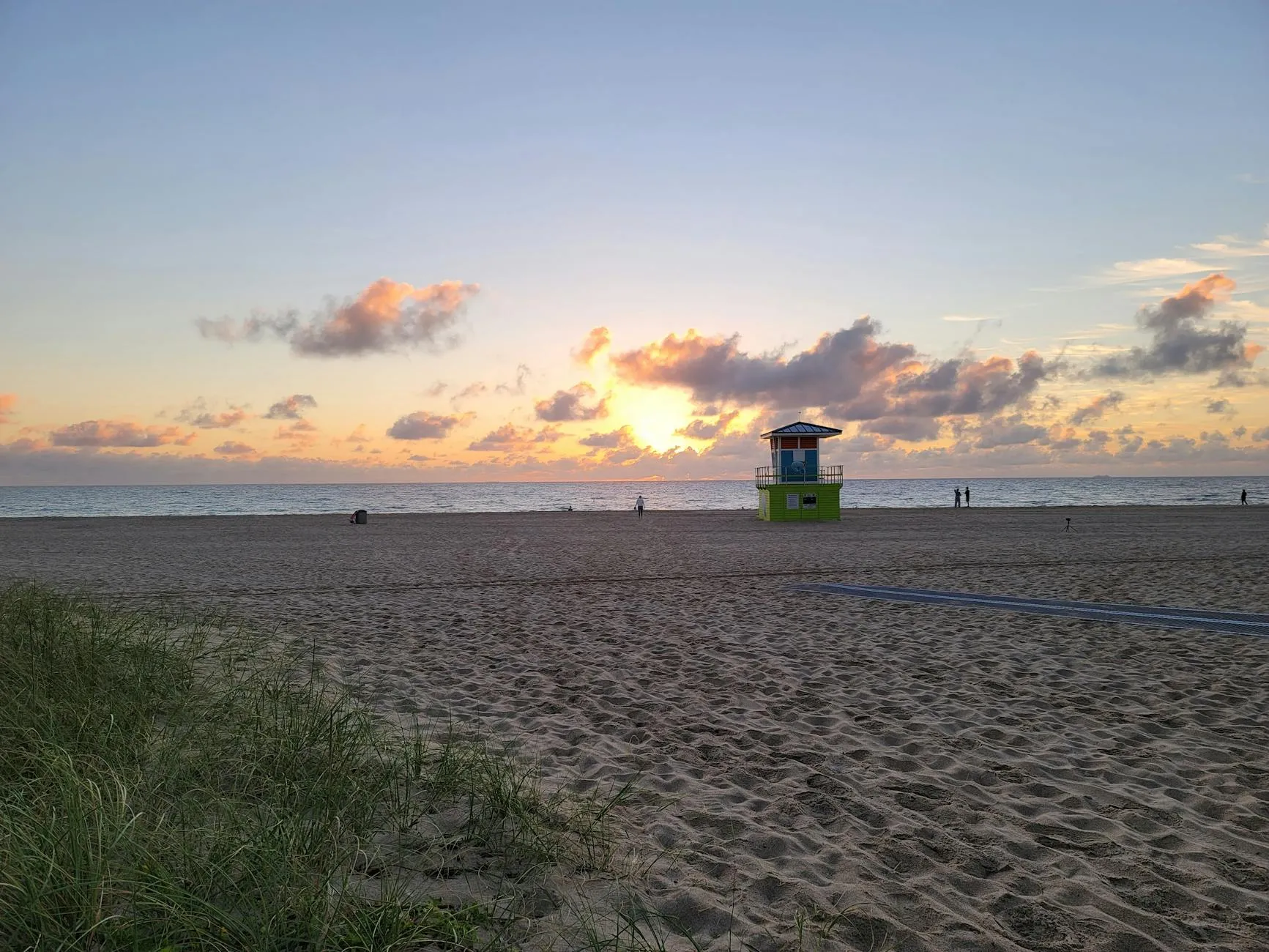 A tranquil sunrise over Fort Lauderdale Beach with a vibrant lifeguard tower and golden sands.
