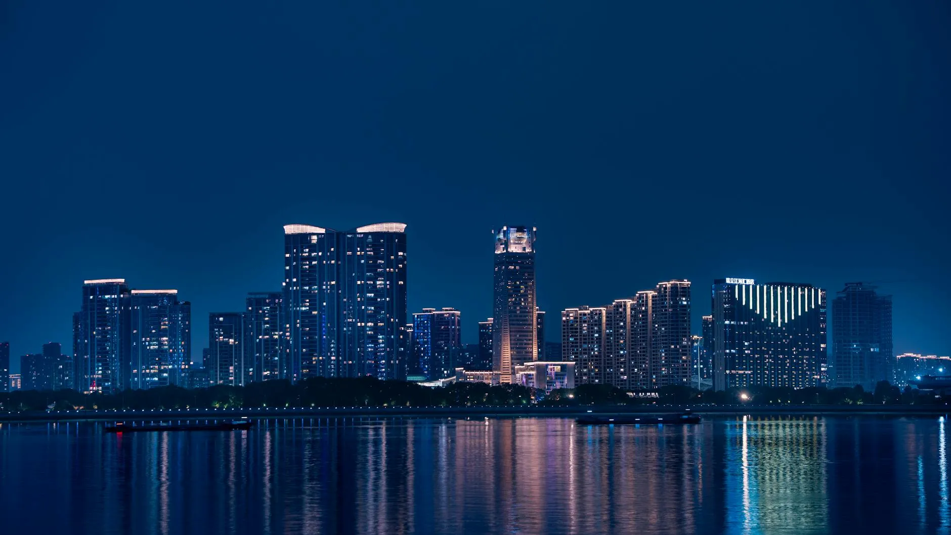 Stunning night view of Hangzhou's skyline reflecting on Qiantang River, showcasing modern architecture.