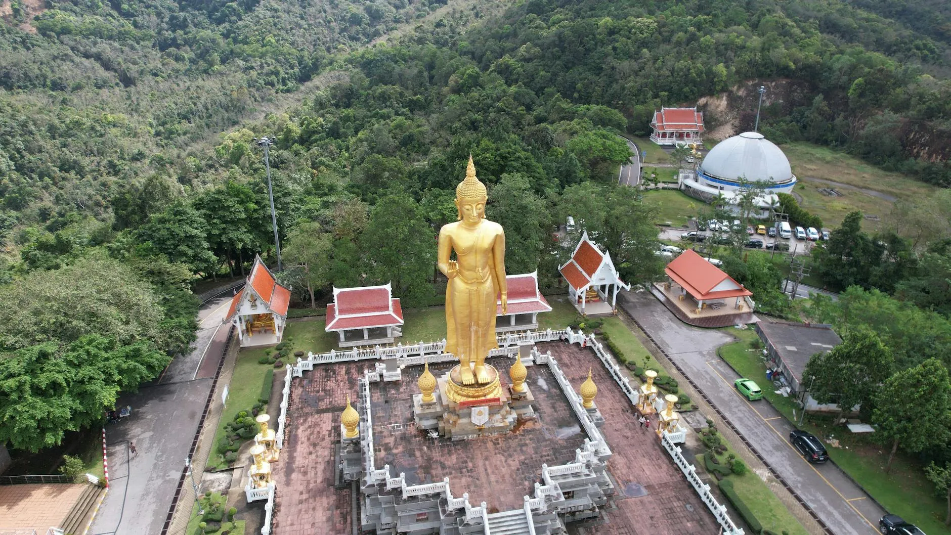 Hat Yai, Thailand — Aerial view of a golden Buddha statue in a temple complex amidst lush forest in Songkhla, Thailand.