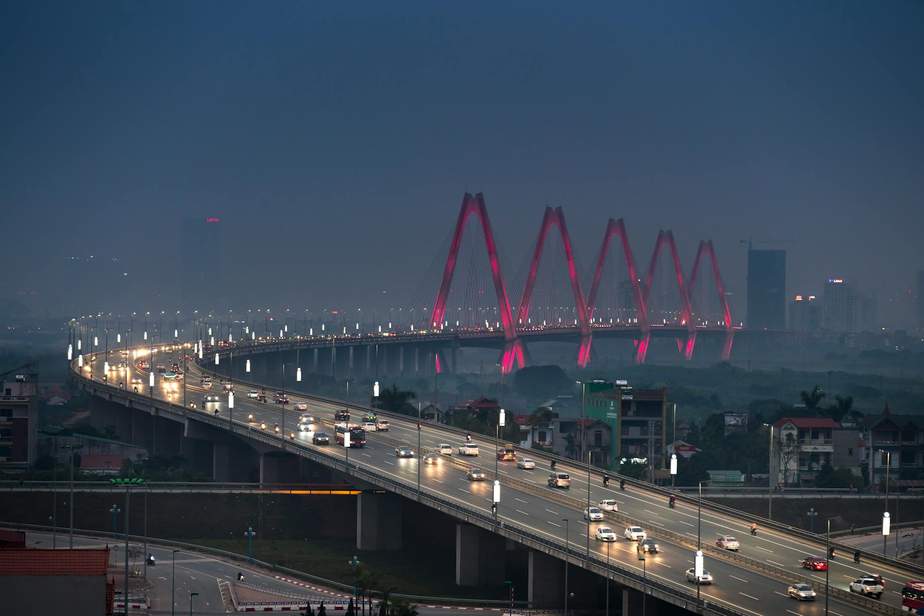 Dramatic aerial view of Hanoi's Nhat Tan Bridge at night, glowing with lights.