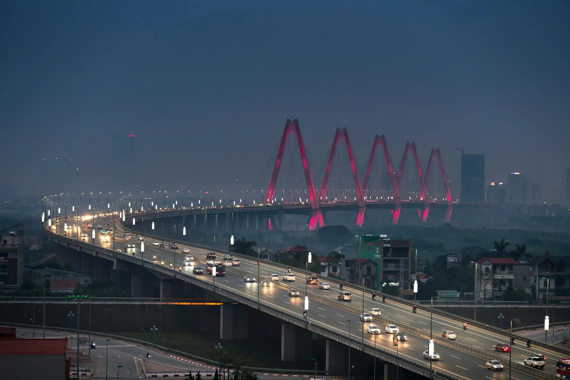 Dramatic aerial view of Hanoi's Nhat Tan Bridge at night, glowing with lights.