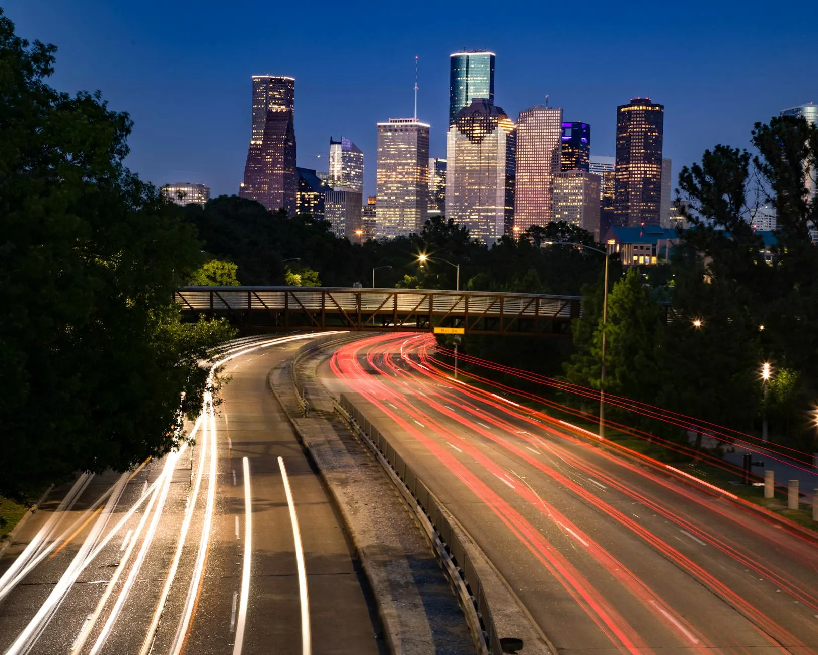 Long exposure shot of Houston's skyline at night with vibrant light trails leading into the city.