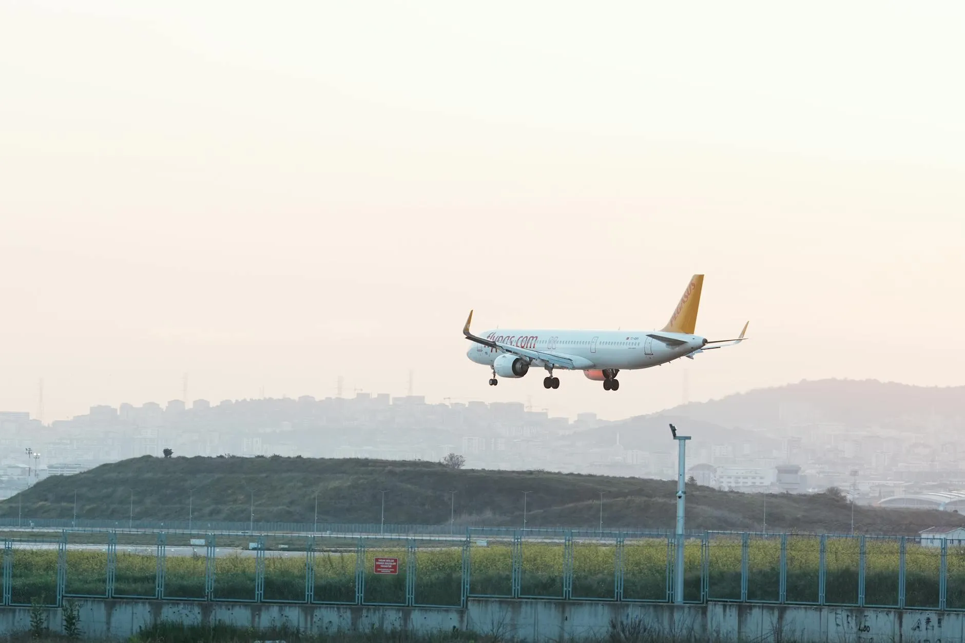 Airplane landing at Istanbul airport during sunset with cityscape background.