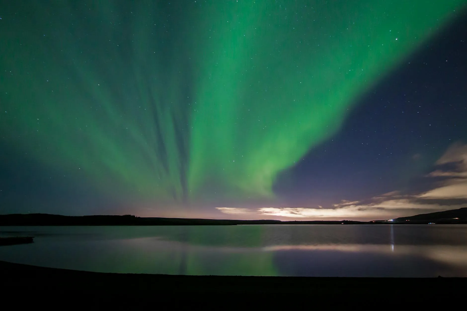 Captivating view of the aurora borealis reflecting over a serene Icelandic lake at night.