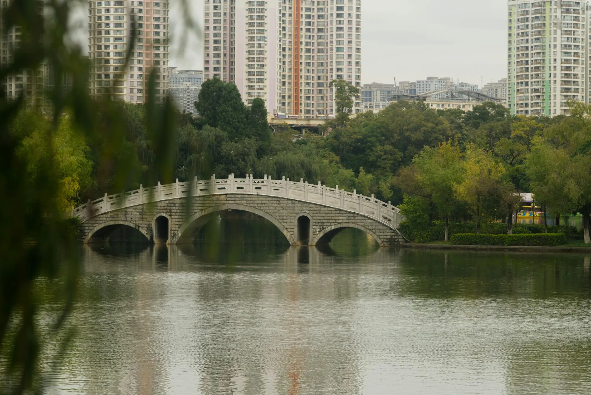 Kunming, China — Beautiful stone arch bridge over peaceful lake with lush greenery in Kunming, Yunnan, China.