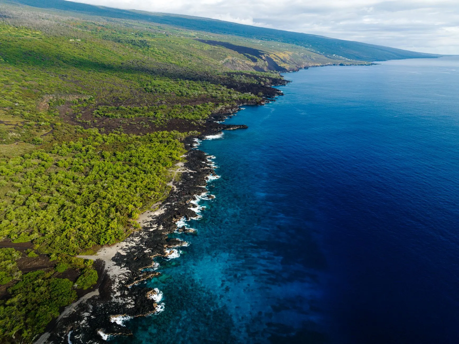 Ellison Onizuka Kona International Airport at Keāhole (KOA) — Stunning aerial view of the lush coastline and blue waters of Honaunau-Napoopoo, Hawaii.
