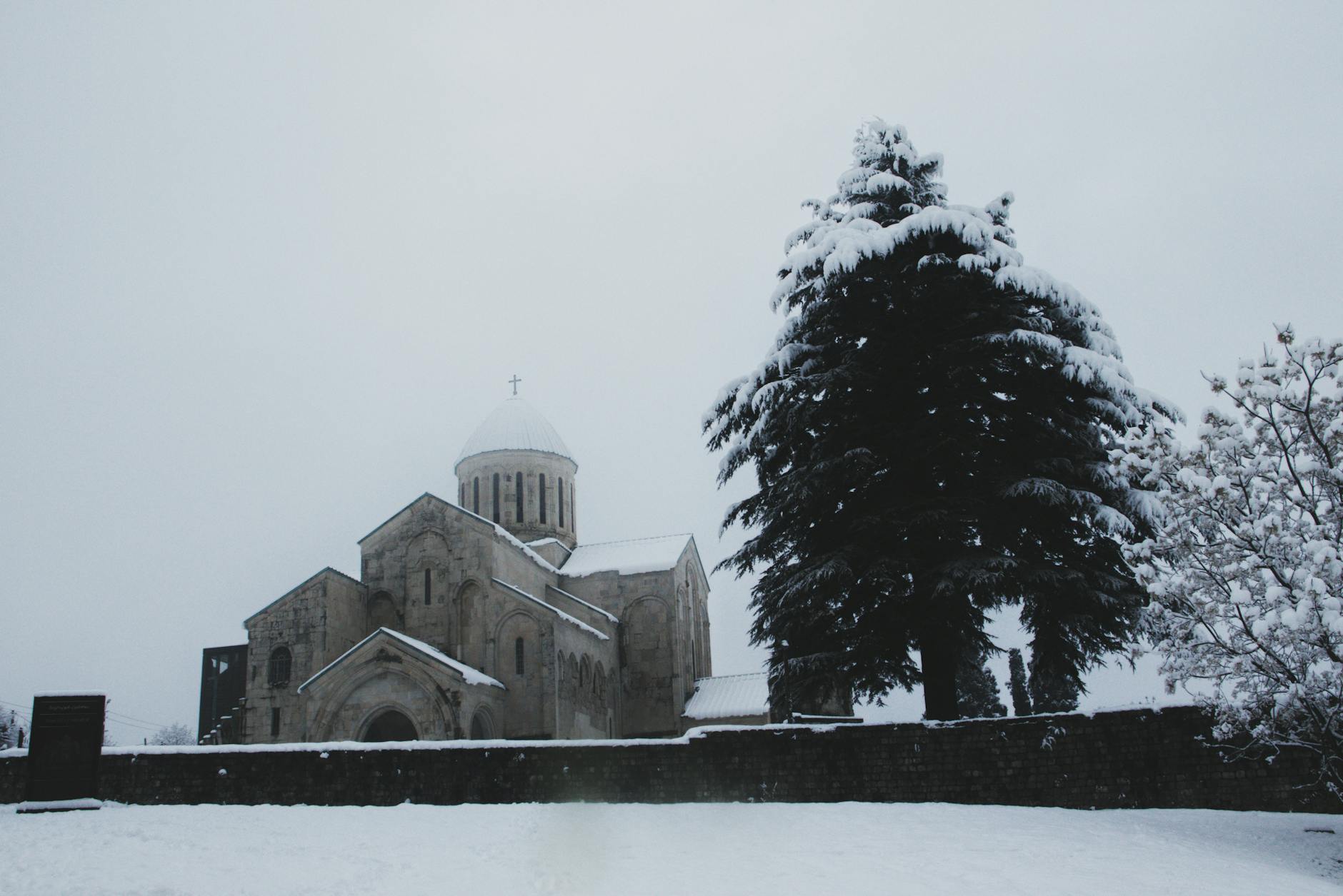 Kutaisi, Georgia — Serene winter view of Gelati Monastery surrounded by snow-covered trees in Kutaisi, Georgia.