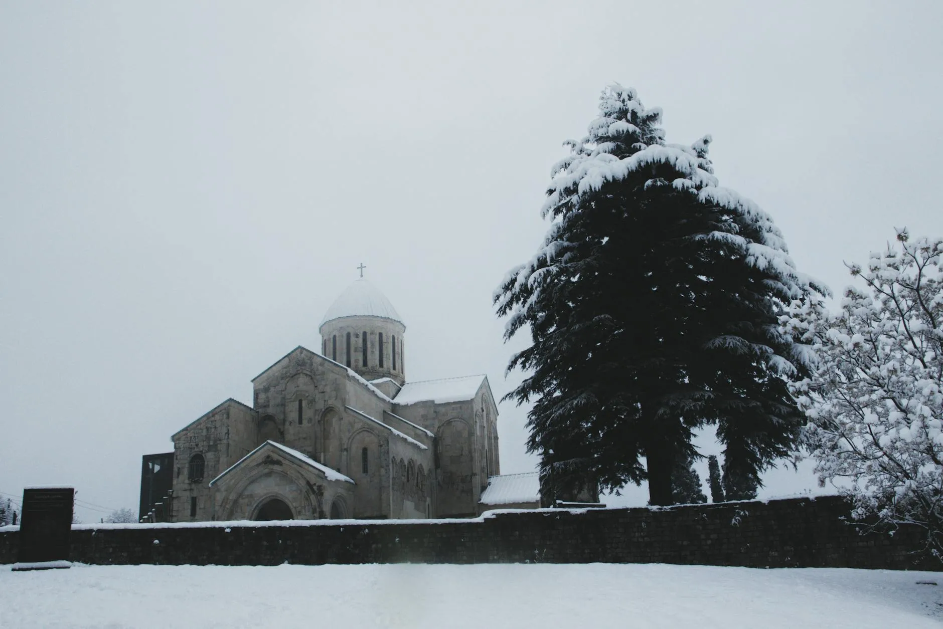 Kutaisi, Georgia — Serene winter view of Gelati Monastery surrounded by snow-covered trees in Kutaisi, Georgia.