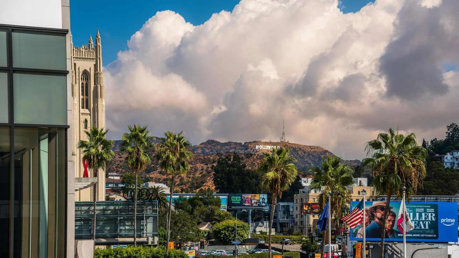 View of the Hollywood Sign with palm trees and city scene in West Hollywood, California.