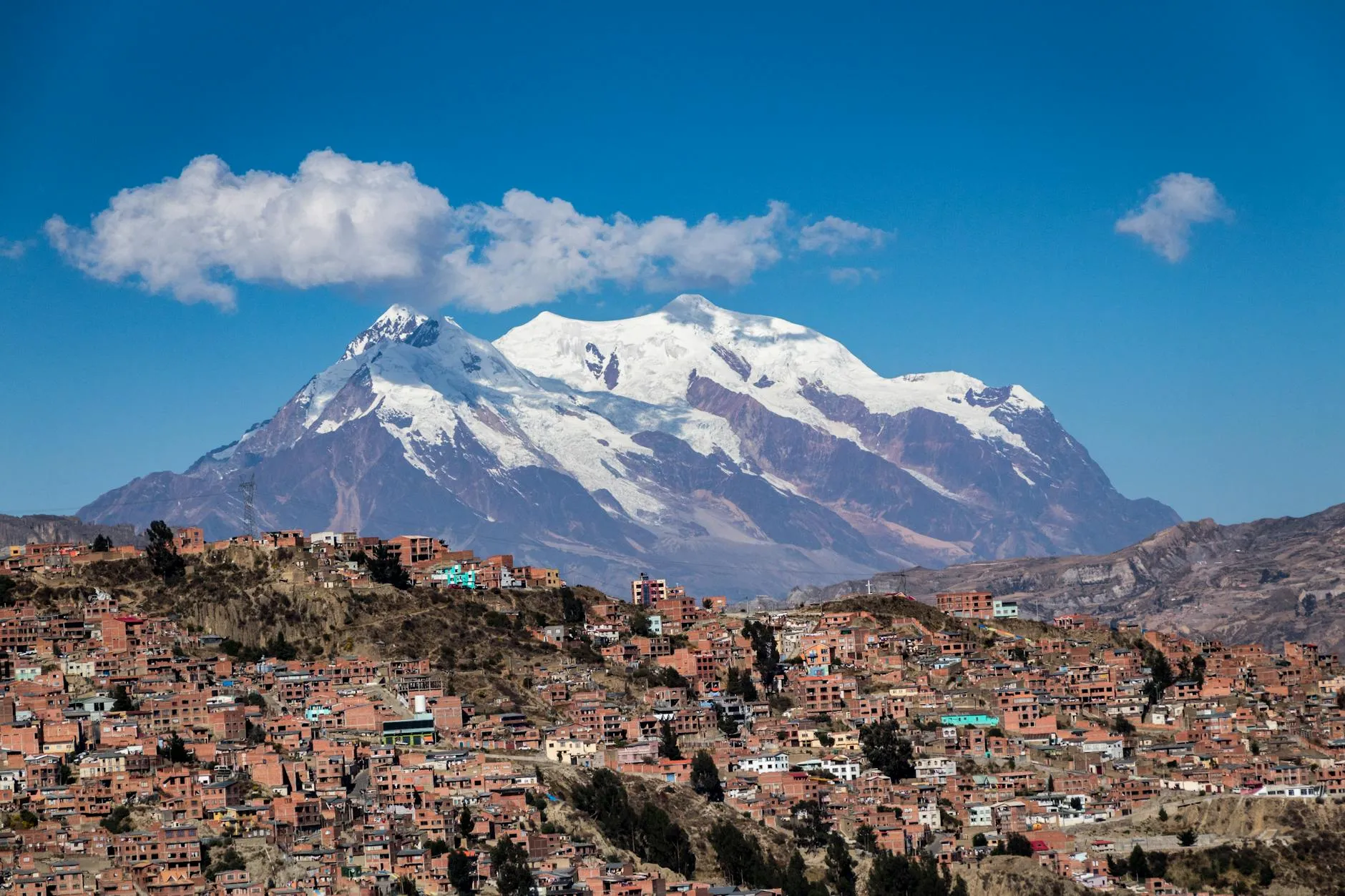 La Paz, Bolivia — Panoramic view of snow-capped Illimani Mountain towering over the vibrant cityscape of La Paz, Bolivia.