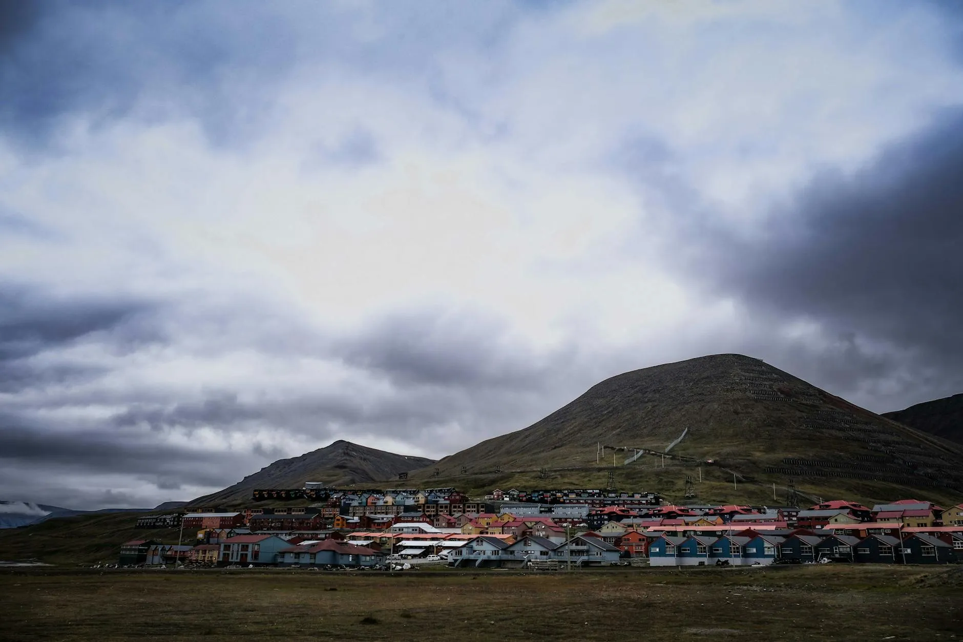 Svalbard Airport (LYR) — A picturesque view of Longyearbyen, Svalbard, with colorful houses and mountains under dramatic clouds.