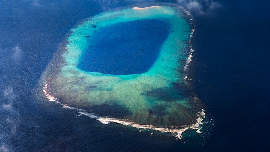 Stunning aerial view of a turquoise lagoon surrounded by vibrant blue ocean and white sandy shores.