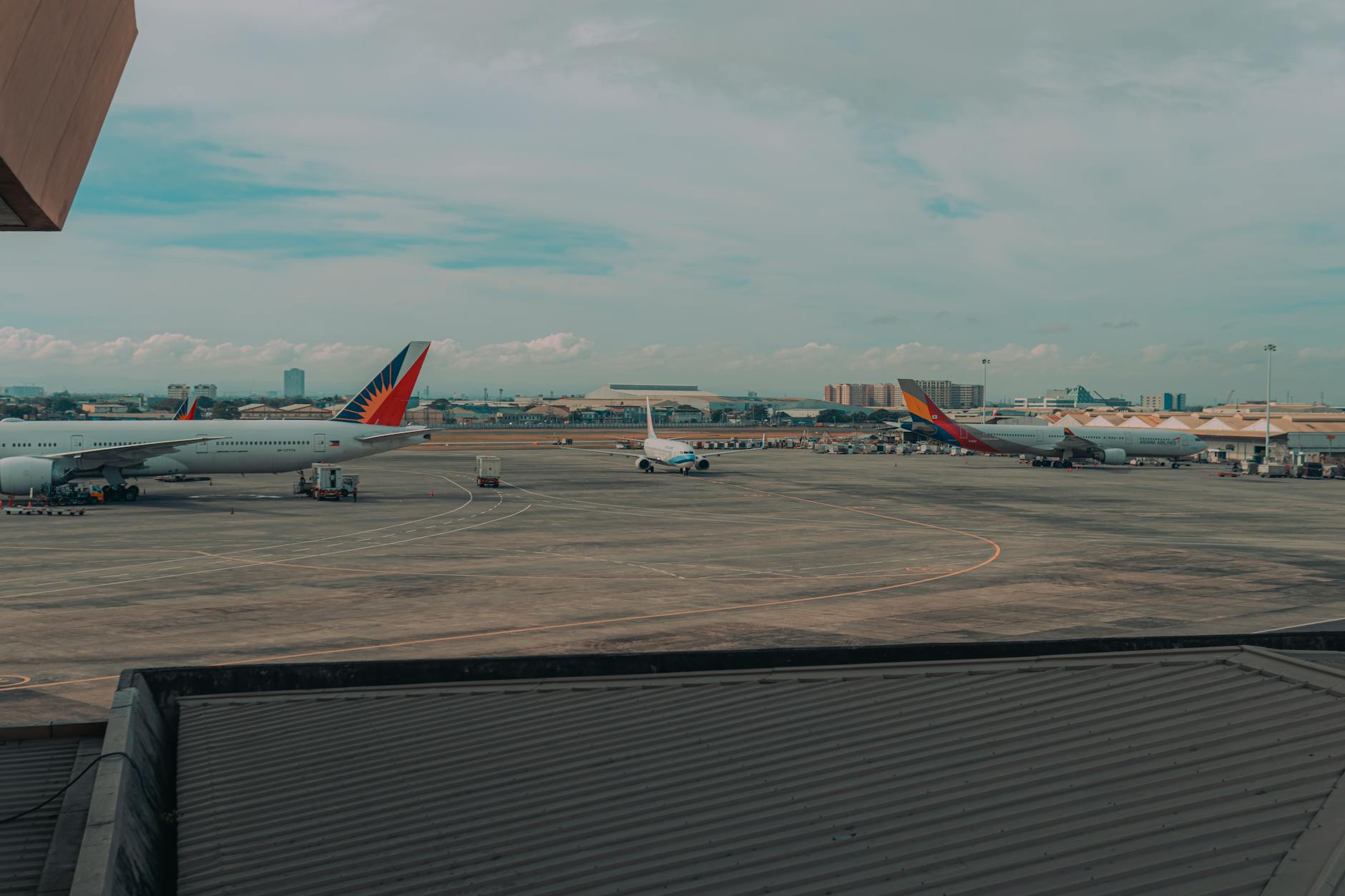 Commercial airplanes parked on an airport tarmac with a cityscape backdrop, capturing a busy travel hub.