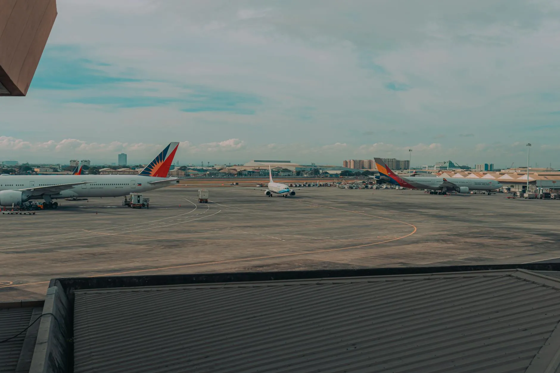 Commercial airplanes parked on an airport tarmac with a cityscape backdrop, capturing a busy travel hub.