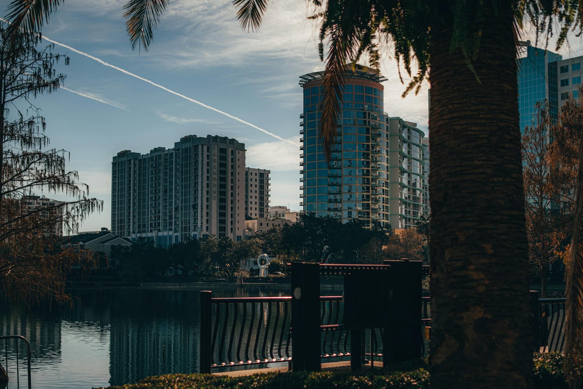 Orlando International Airport (MCO) — View of Orlando's modern skyline reflecting on a tranquil lake, surrounded by trees.