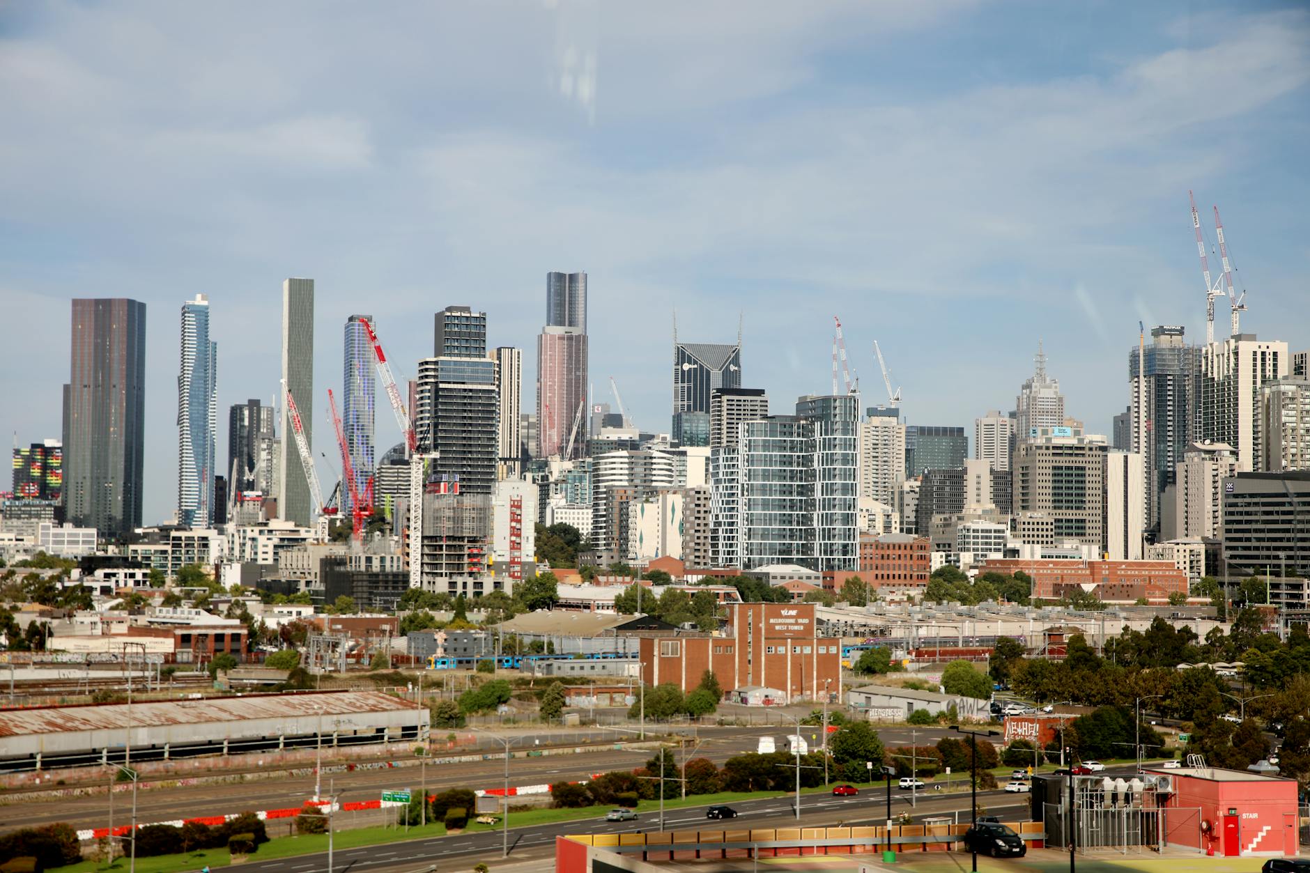 View of Melbourne's skyline featuring tall skyscrapers and construction cranes under a clear sky.