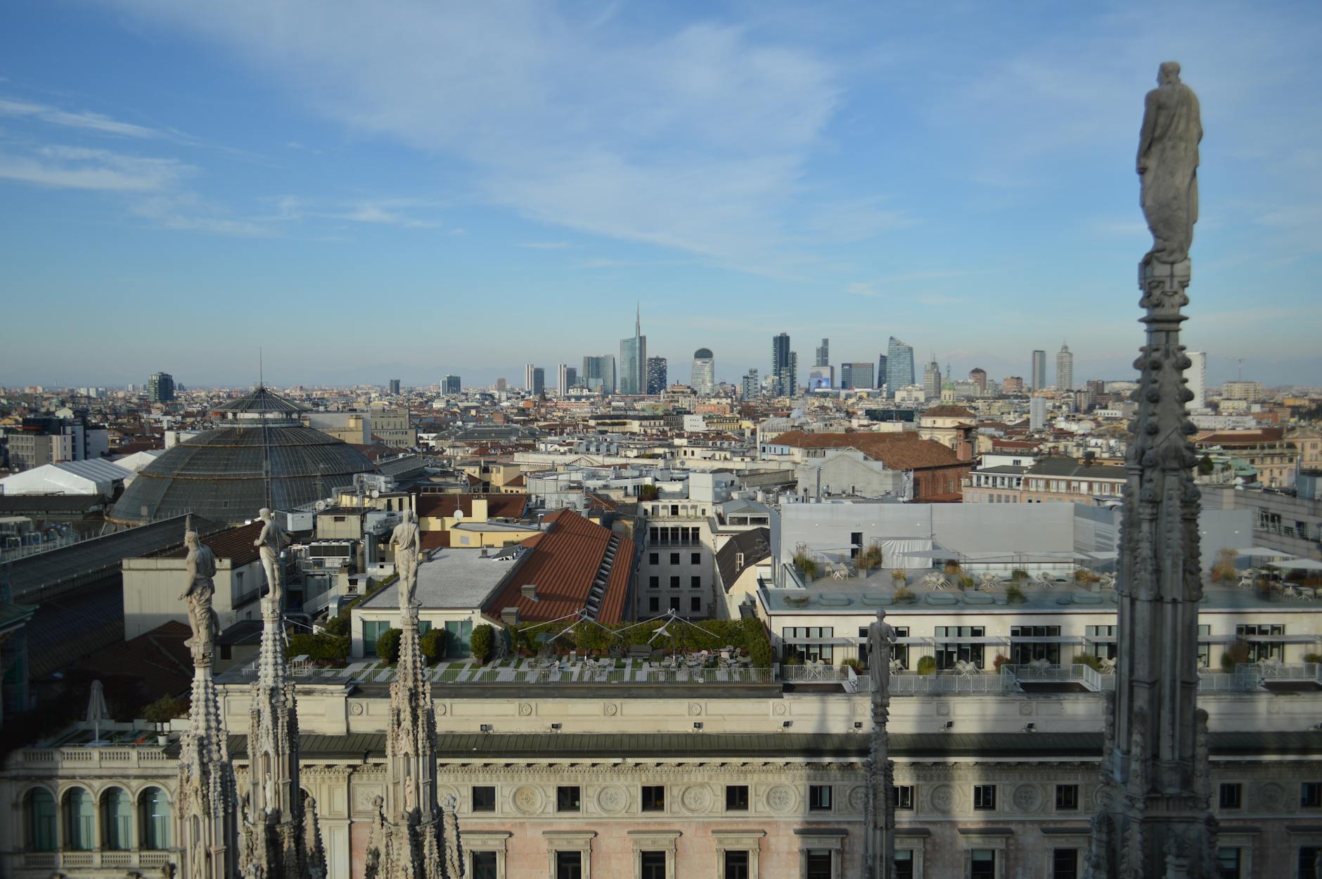 Captivating aerial view of Milan's skyline from atop the Duomo with a clear blue sky backdrop.