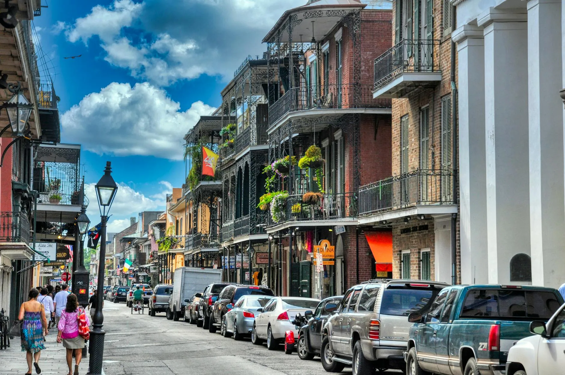 Louis Armstrong New Orleans International Airport (MSY) — Vibrant day in New Orleans' French Quarter with people walking and historic architecture lining the street.