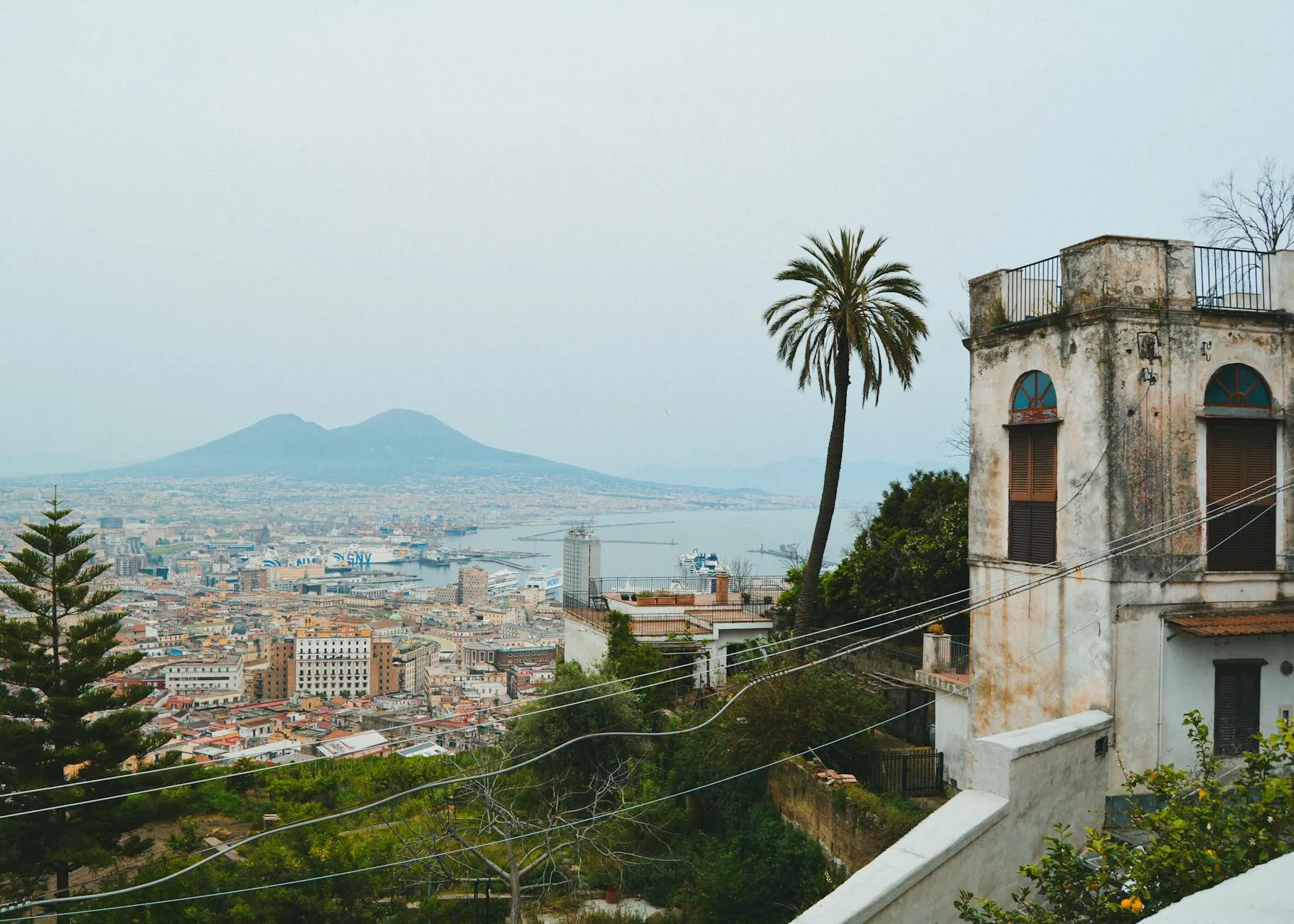 A picturesque view of Naples with Mount Vesuvius and historic architecture in the foreground.