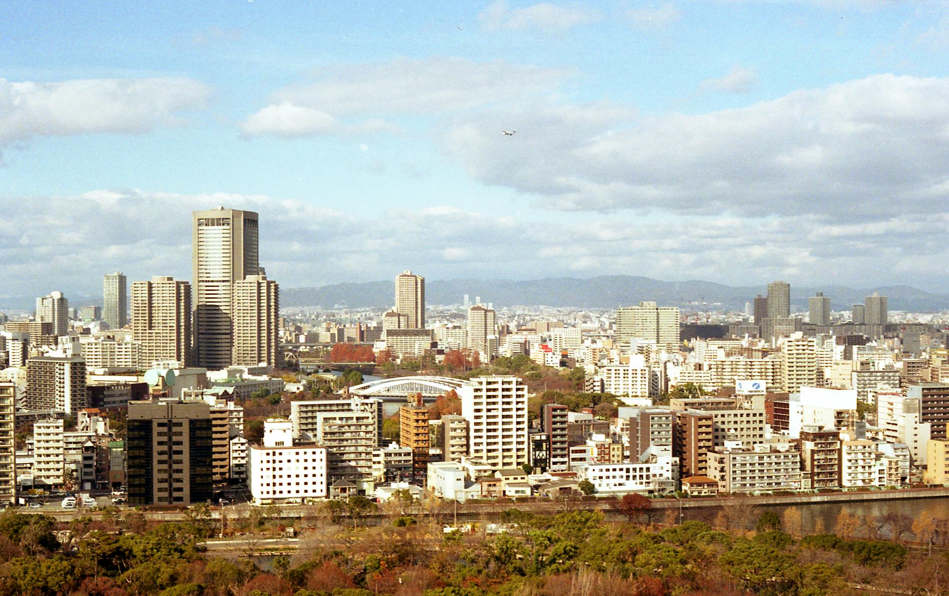 Explore the vibrant skyline of Osaka City with its modern architecture and lush autumn foliage.