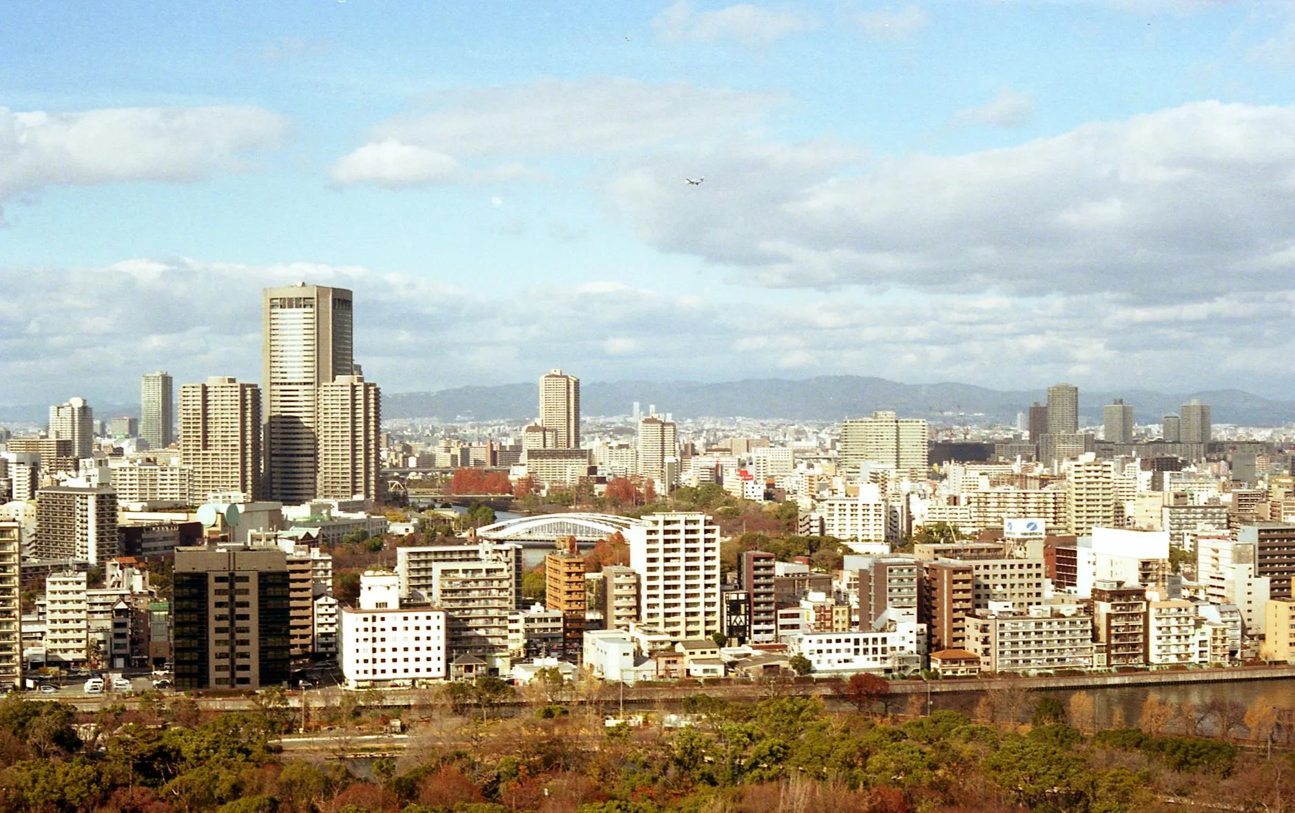 Explore the vibrant skyline of Osaka City with its modern architecture and lush autumn foliage.