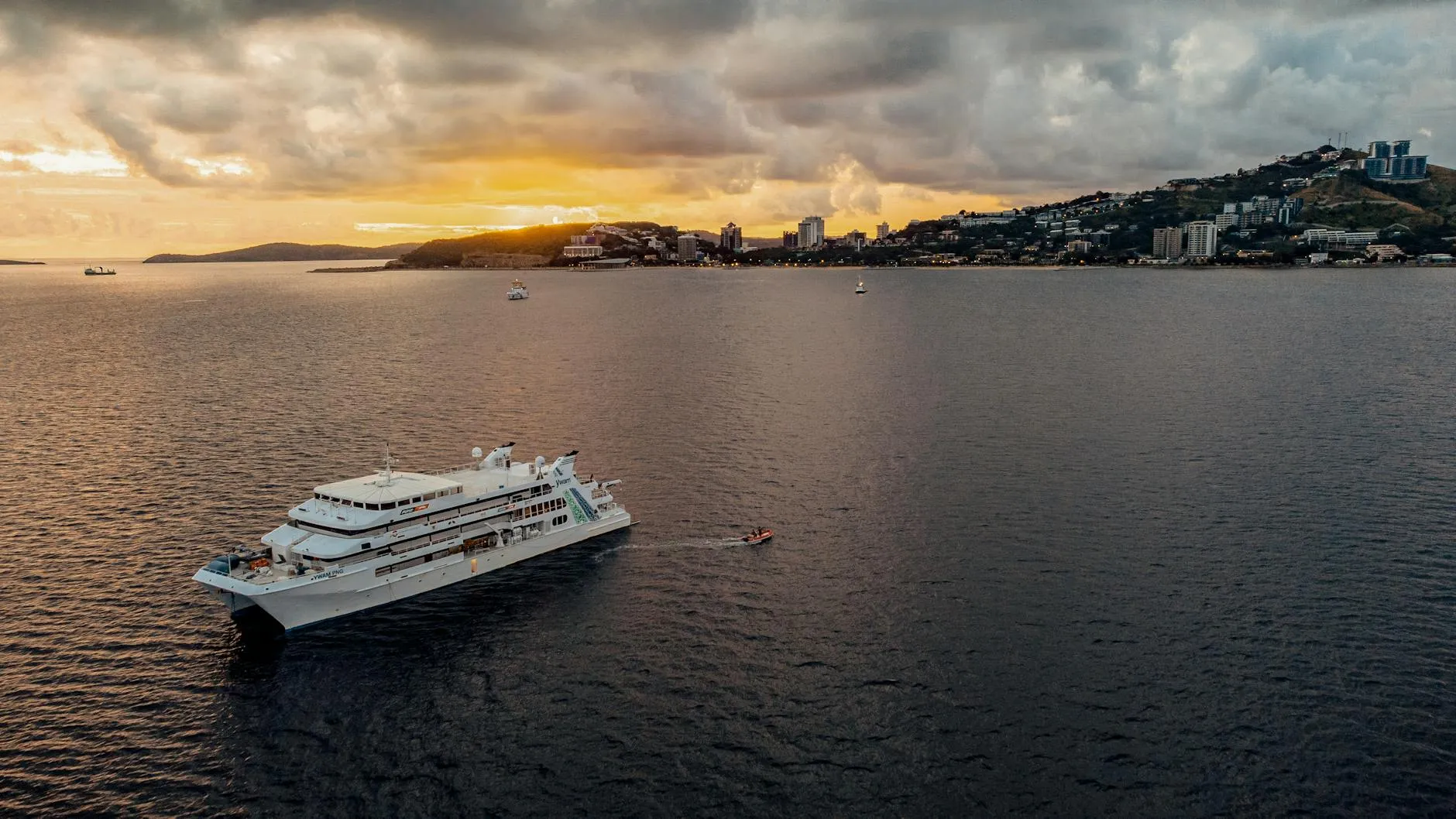 Port Moresby, Papua New Guinea — A cruise ship sails in Port Moresby harbor at sunset, Papua New Guinea.