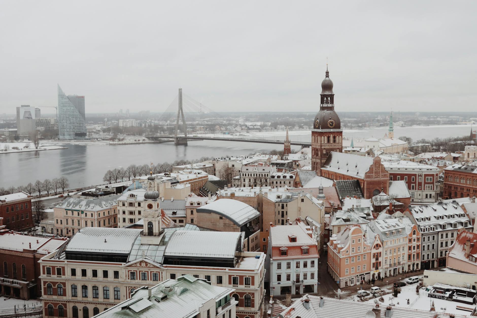 Aerial shot of snow-covered Old Town Riga with the Daugava River and iconic architecture in winter.