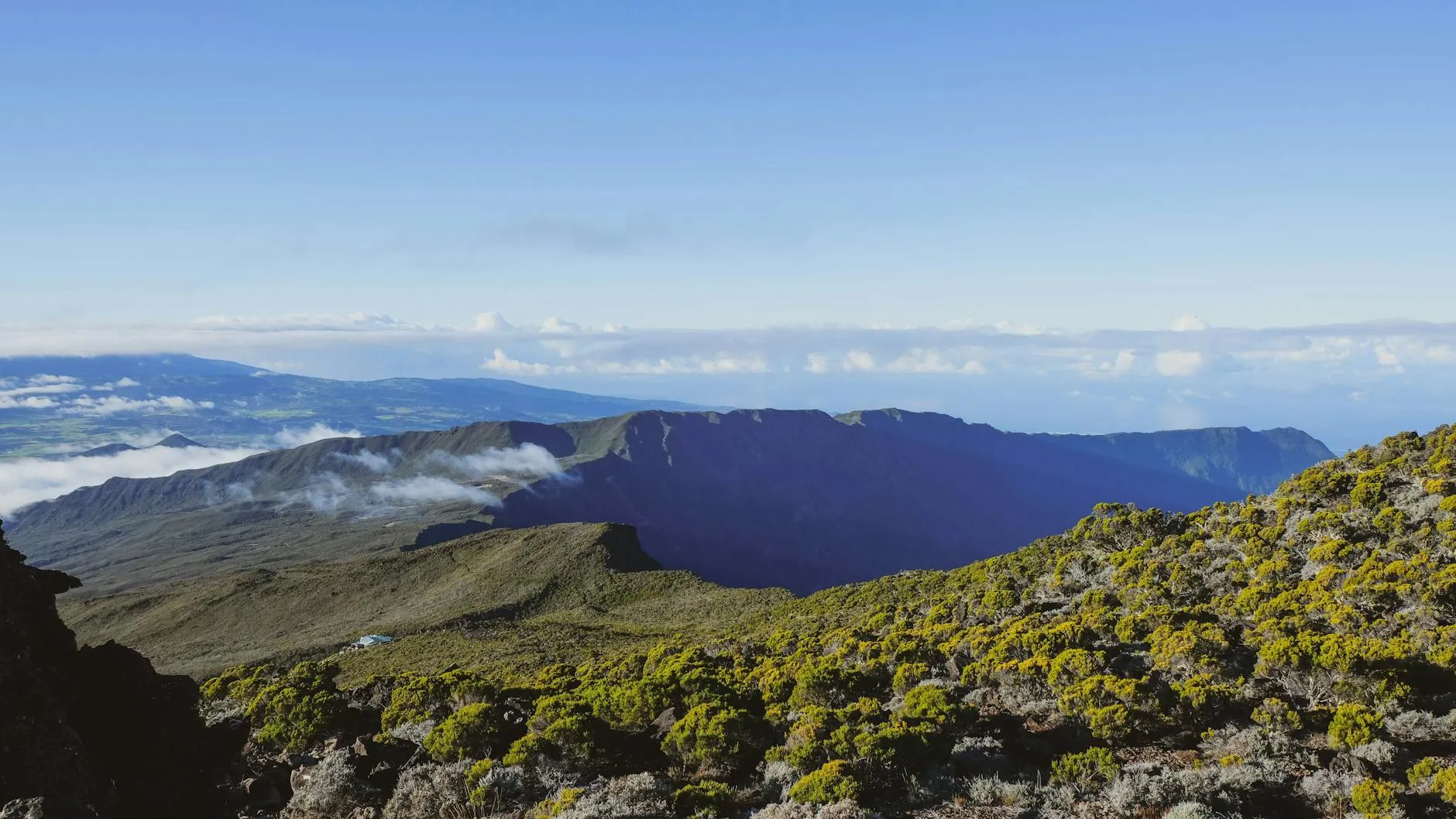 Roland Garros Airport (RUN) — Stunning aerial view of a volcanic landscape on Réunion Island with lush greenery and clear skies.