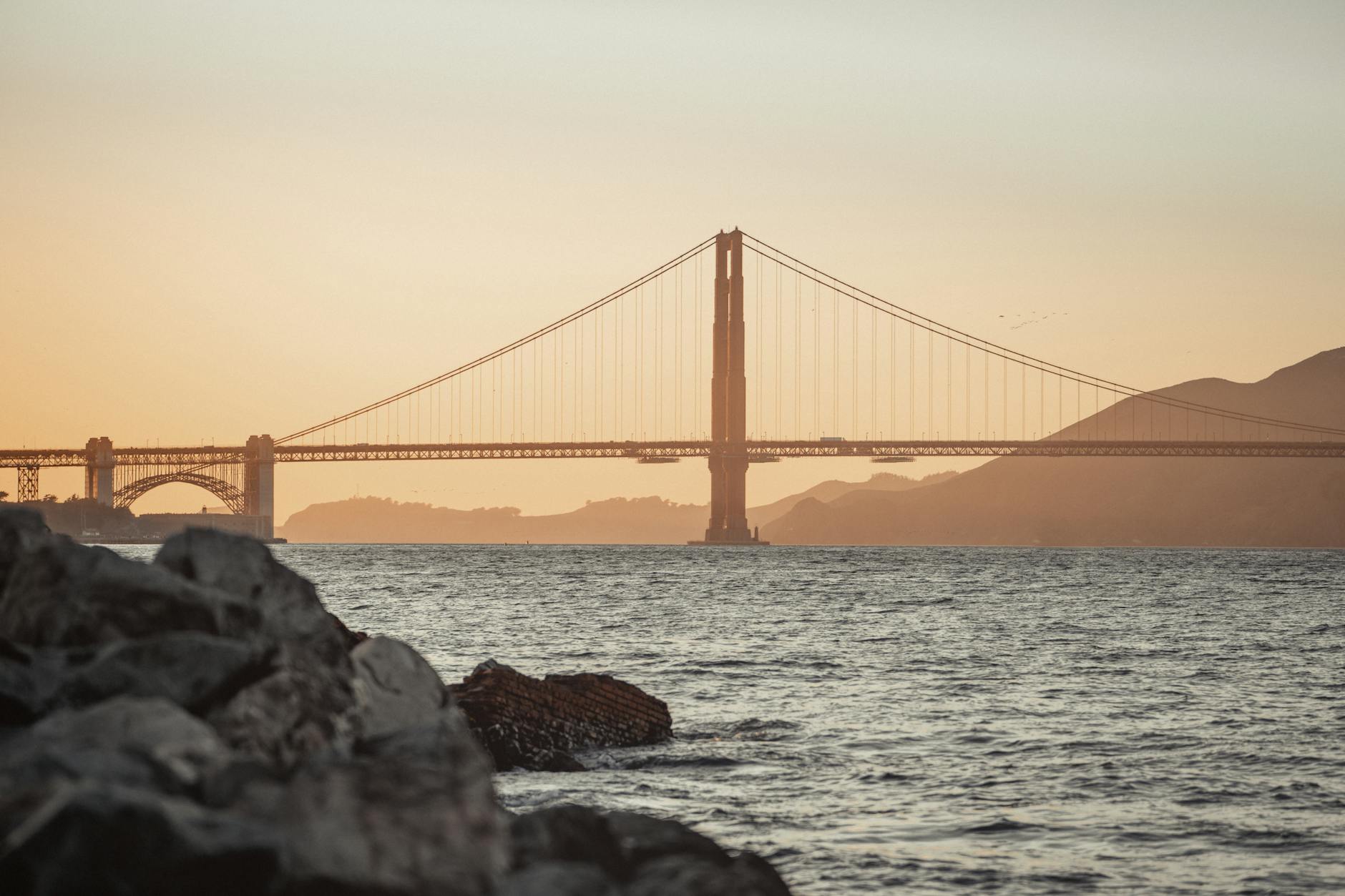 Iconic view of the Golden Gate Bridge during sunset in San Francisco, showcasing the serene bay and stunning skyline.